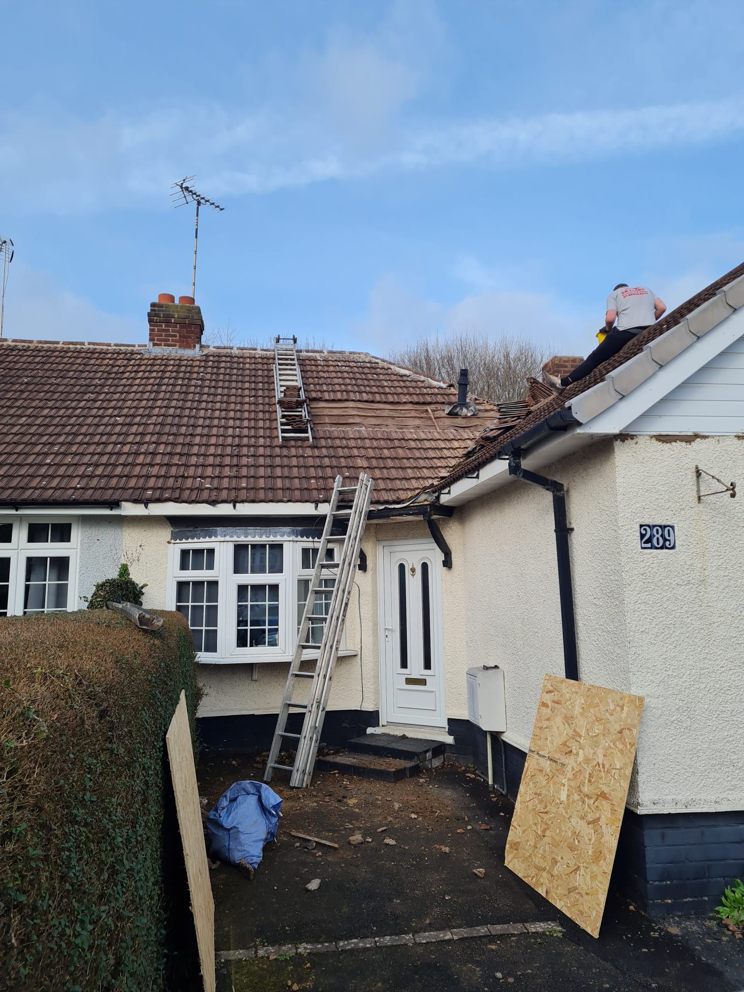 Re-roofing work in progress with worker on bungalow roof